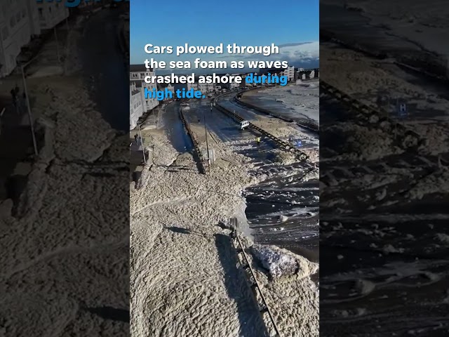 Cars navigate flooded road covered in sea foam after storm #Shorts