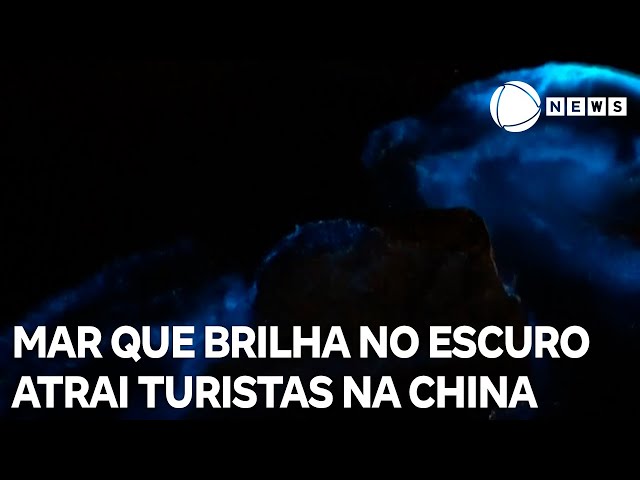 Turistas brincam em mar que brilha no escuro na China