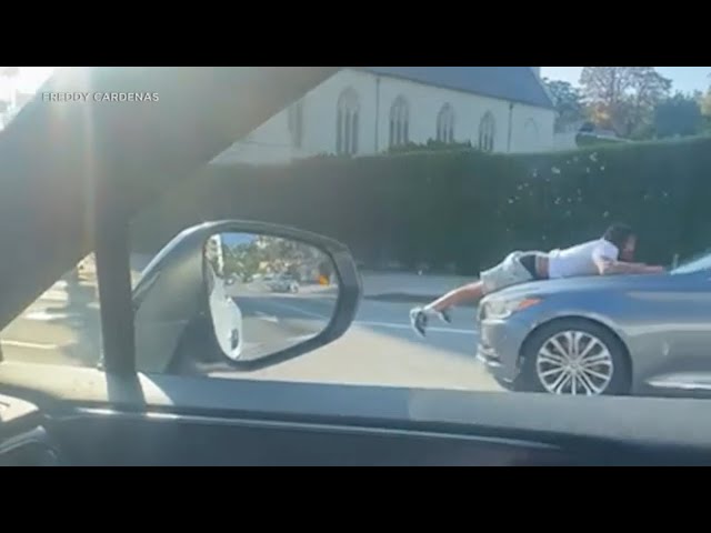⁣Bizarre video shows man clinging to hood of moving car in Hollywood