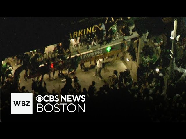 Celtics fans climb parking garage sign by TD Garden after win