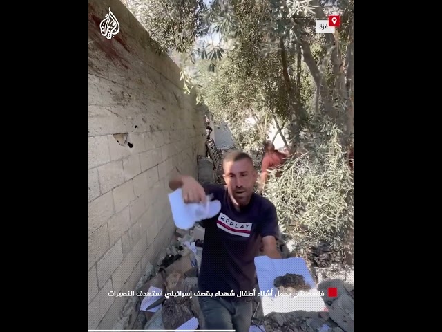 فلسطيني يحمل أشلاء أطفال شهداء بقصف إسرائيلي استهدف النصيرات