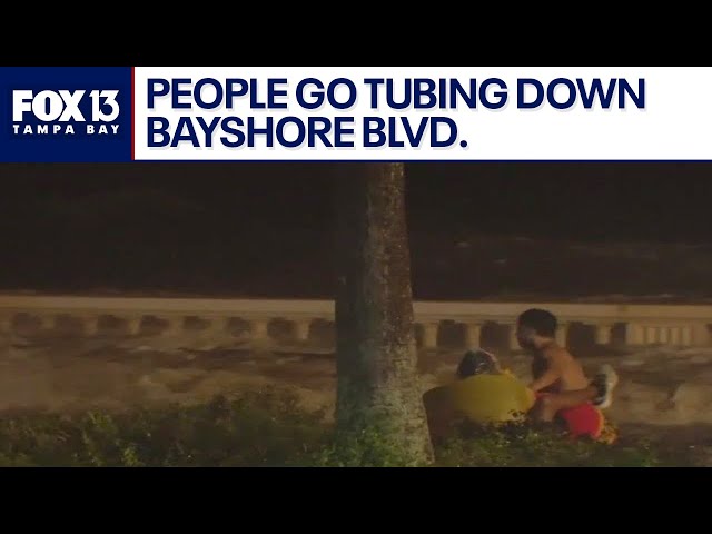 People ride the waves in tubes down Bayshore Boulevard