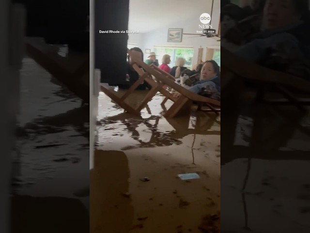 ⁣Group of people and pets stand in chest-high water inside North Carolina home